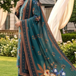 Side profile of a smiling model walking on a garden lawn wearing a teal spruce 3 piece elegent summer lawn suit, showcasing a long draped dupatta with detailed geometric borders and decorative pallu corners.