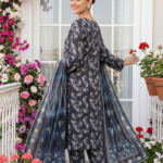 Back view of a model looking over her shoulder wearing the ginkgo maze 3 piece premium lawn suit, highlighting the continuous fan leaf print on the trousers and the fully flared chevron stripe and polka dot dupatta.