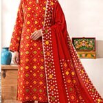 Model posing in a matching 3-piece fiery crimson red indus dot chunri lawn suit with a printed border dupatta.