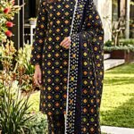 Model posing in a matching 3-piece midnight black indus dot chunri lawn suit with orange and green geometric details.