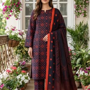 Model posing outdoors wearing a matching 3-piece navy blue indigo rouge premium summer lawn suit with red geometric prints and an ombré dupatta.