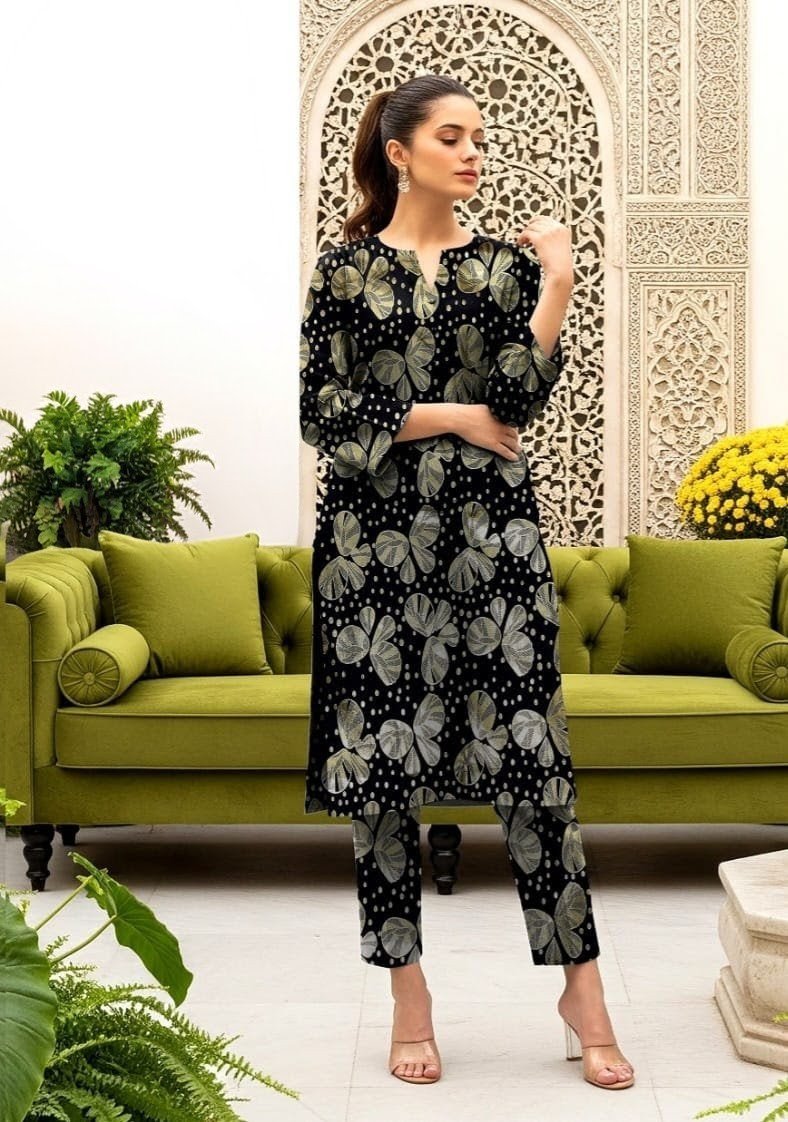 Model posing near a green sofa in the black variant of the monarch foil 2 piece premium summer lawn suit with olive prints.