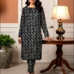 Model standing by a table lamp wearing the jet black variant of the ivy bunch 2 piece premium summer lawn suit with pale mint prints.