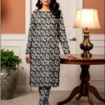 Model standing by a table lamp wearing the charcoal grey variant of the ivy bunch 2 piece premium summer lawn suit with soft ivory prints.