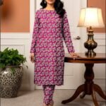 Model standing by a table lamp wearing the magenta pink variant of the ivy bunch 2 piece premium summer lawn suit with light cream prints.