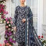 Model standing near a white glass door window wearing a matching 3-piece charcoal indigo ginkgo maze premium lawn suit with silver fan prints and a chevron patterned polka dot dupatta.